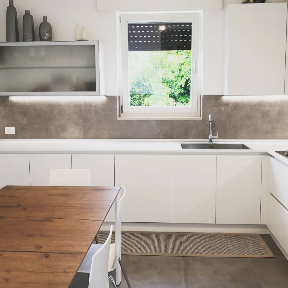 Large contemporary l-shaped eat-in kitchen in Other with a drop-in sink, flat-panel cabinets, white cabinets, laminate benchtops, grey splashback, porcelain splashback, stainless steel appliances, porcelain floors, grey floor and white benchtop.