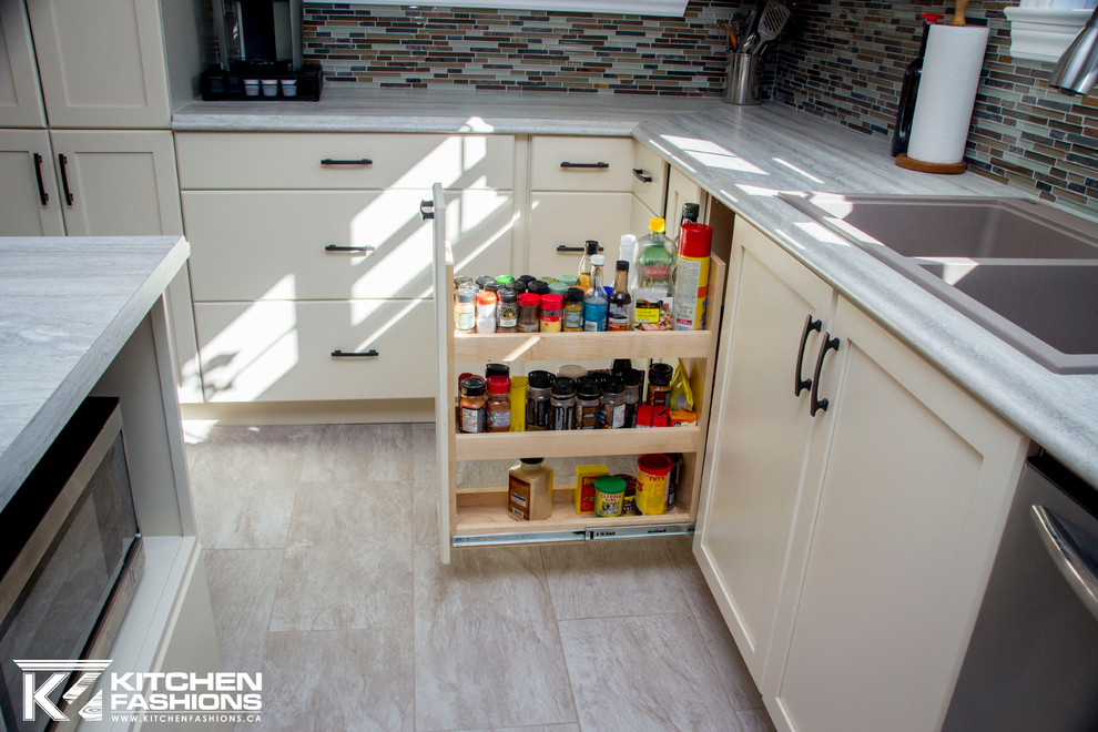 Open concept kitchen - large contemporary u-shaped vinyl floor open concept kitchen idea with a drop-in sink, shaker cabinets, beige cabinets, laminate countertops, multicolored backsplash, glass tile backsplash, stainless steel appliances and an island