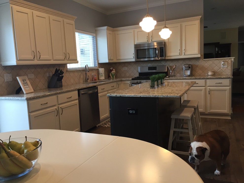 Kitchen - mid-sized transitional laminate floor kitchen idea in Chicago with an undermount sink, recessed-panel cabinets, granite countertops, beige backsplash, stone tile backsplash, stainless steel appliances and an island