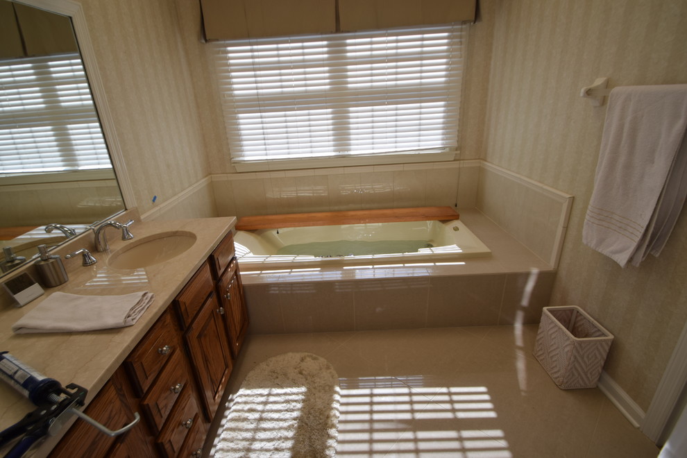 Example of a mid-sized transitional kids' gray tile and porcelain tile porcelain tile and gray floor drop-in bathtub design with raised-panel cabinets, medium tone wood cabinets, a one-piece toilet, blue walls, an undermount sink, granite countertops and multicolored countertops