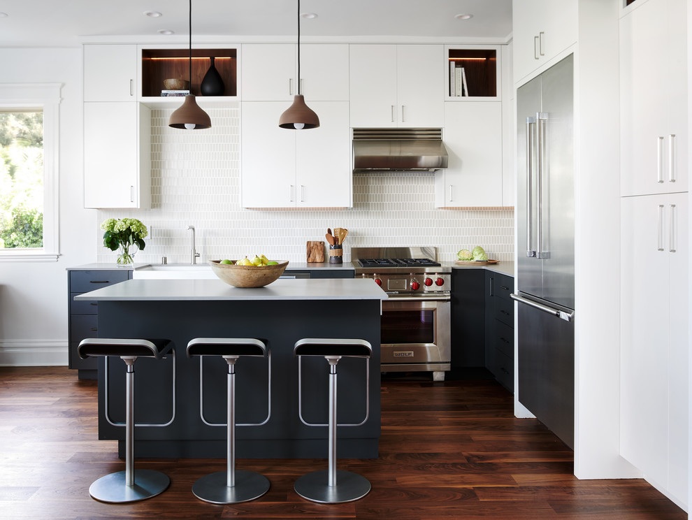 Inspiration for a mid-sized contemporary l-shaped eat-in kitchen in San Francisco with a farmhouse sink, flat-panel cabinets, quartz benchtops, ceramic splashback, stainless steel appliances, with island, brown floor, grey benchtop, white splashback and dark hardwood floors.