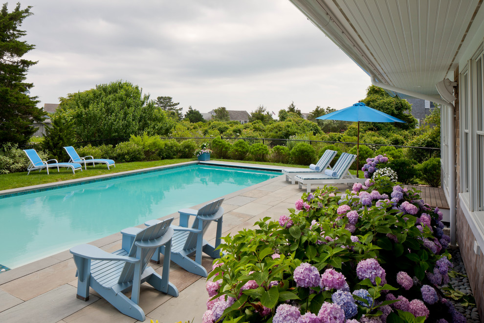 This is an example of a large traditional rectangular lap pool in Boston with a hot tub and concrete pavers.