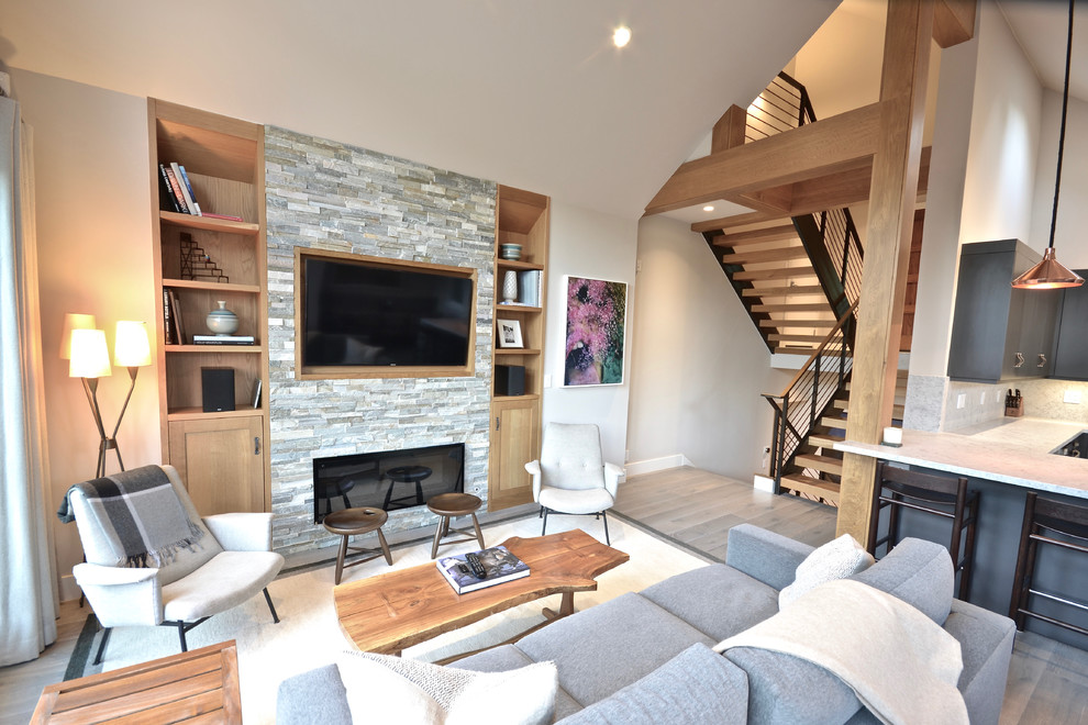 This is an example of a transitional open concept living room in Salt Lake City with light hardwood floors, a stone fireplace surround and a built-in media wall.