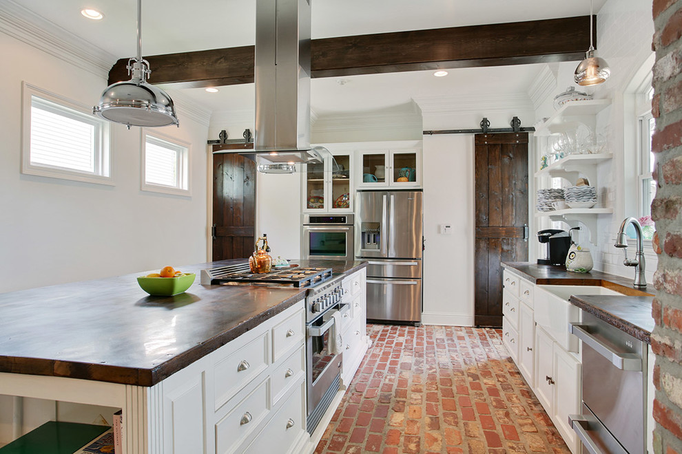 Design ideas for a large traditional u-shaped separate kitchen in New Orleans with a farmhouse sink, glass-front cabinets, white cabinets, granite benchtops, stainless steel appliances, brick floors, with island and red floor.