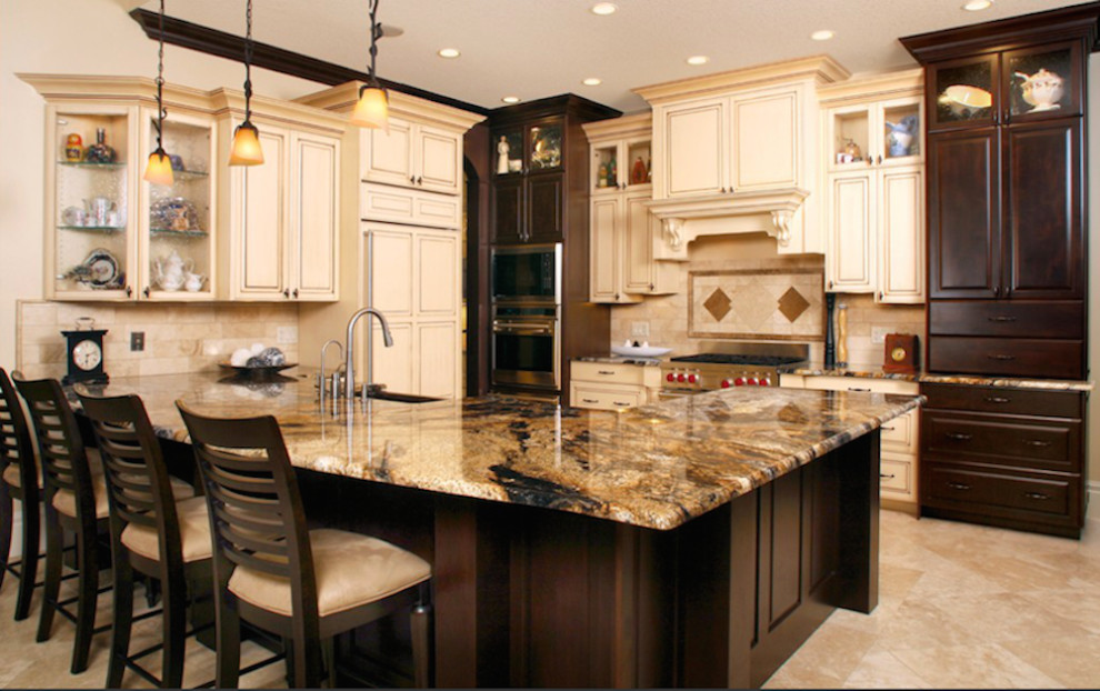 This is an example of a large traditional l-shaped open plan kitchen in Sacramento with an undermount sink, raised-panel cabinets, beige cabinets, granite benchtops, beige splashback, subway tile splashback, stainless steel appliances, travertine floors and a peninsula.