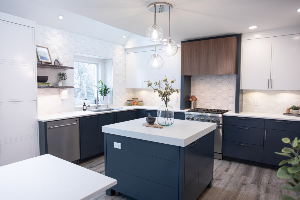 Design ideas for a mid-sized contemporary u-shaped eat-in kitchen in Omaha with a single-bowl sink, shaker cabinets, white cabinets, quartz benchtops, white splashback, ceramic splashback, stainless steel appliances, vinyl floors, with island, brown floor and grey benchtop.