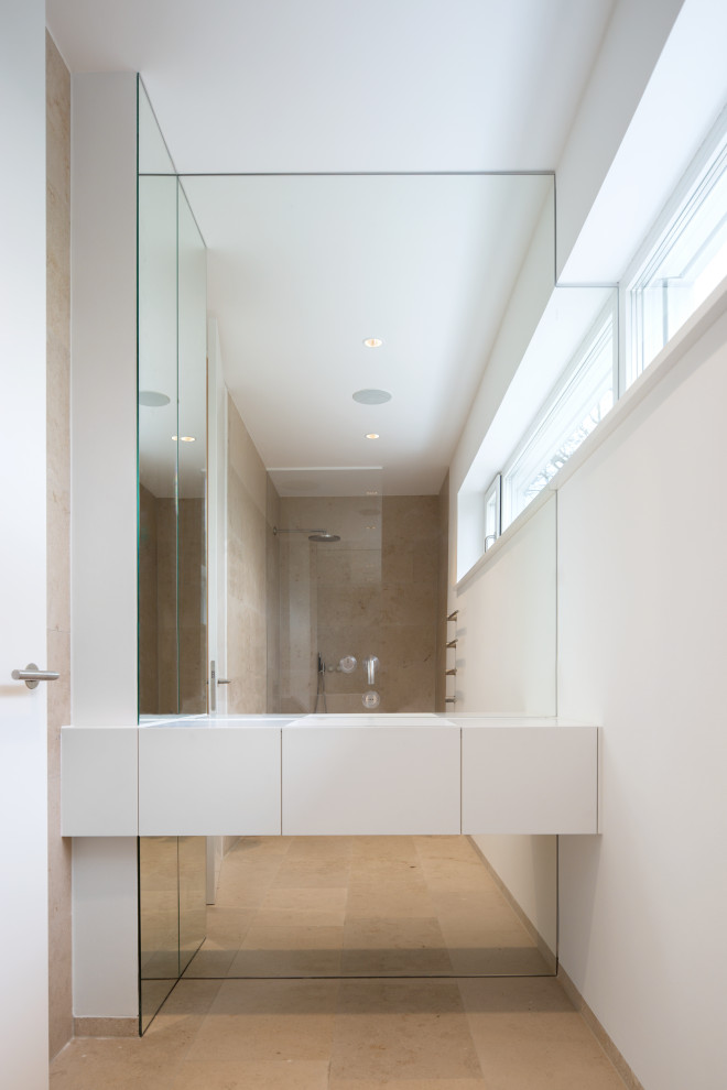 Идея дизайна: туалет в стиле модернизм с плоскими фасадами, белыми фасадами, полом из известняка, монолитной раковиной, столешницей из искусственного камня, бежевым полом, белой столешницей и подвесной тумбой