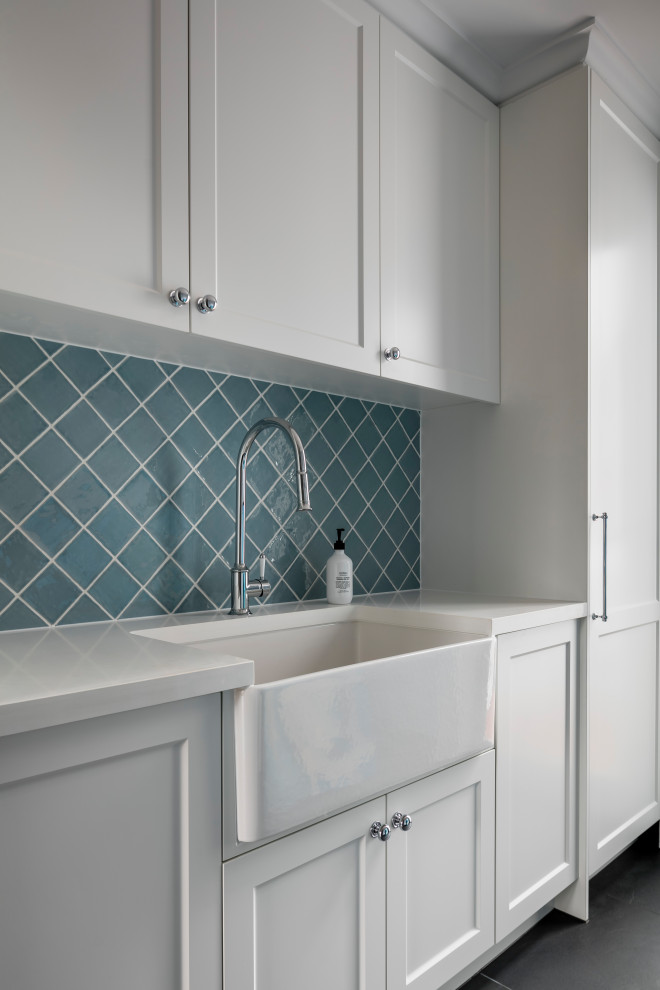 This is an example of a mid-sized contemporary laundry room in Melbourne with a farmhouse sink, shaker cabinets, white cabinets, quartz benchtops, blue splashback, mosaic tile splashback and white benchtop.