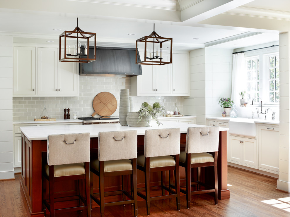 Design ideas for a mid-sized transitional u-shaped kitchen in Atlanta with with island, a farmhouse sink, beaded inset cabinets, white cabinets, grey splashback, subway tile splashback, stainless steel appliances, medium hardwood floors, marble benchtops and brown floor.