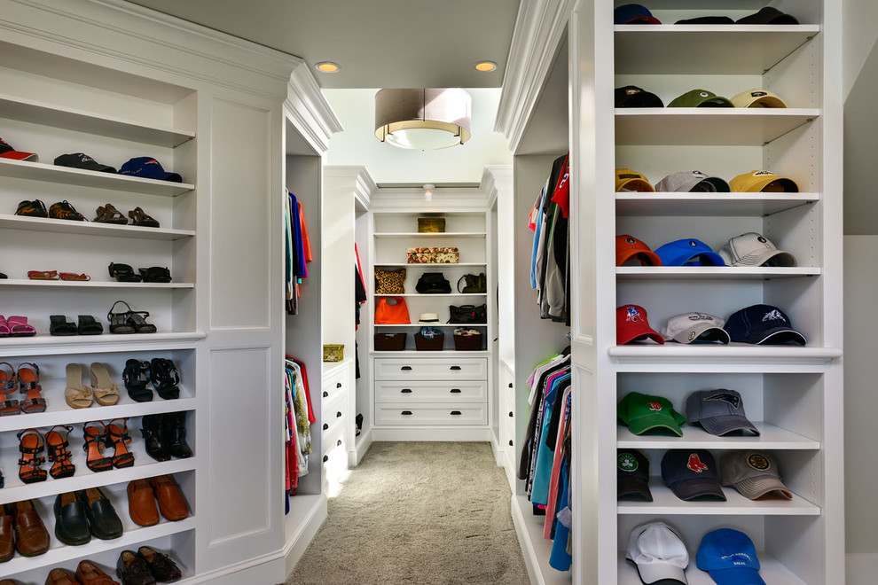 This is an example of a large beach style gender-neutral walk-in wardrobe in Boston with open cabinets, white cabinets and carpet.