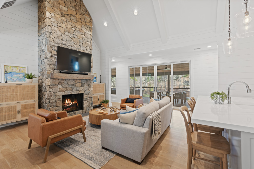 Photo of a beach style living room in Other with white walls, a stone fireplace surround, brown floors, exposed beams and tongue and groove walls.