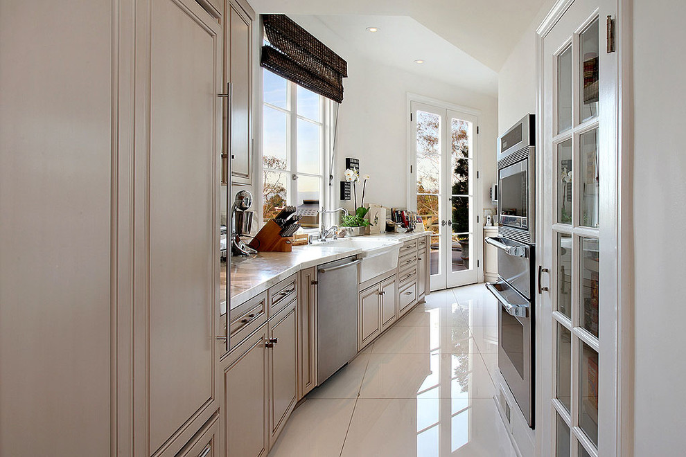 Photo of a small contemporary galley kitchen in Los Angeles with raised-panel cabinets, beige cabinets, marble benchtops, stainless steel appliances and with island.