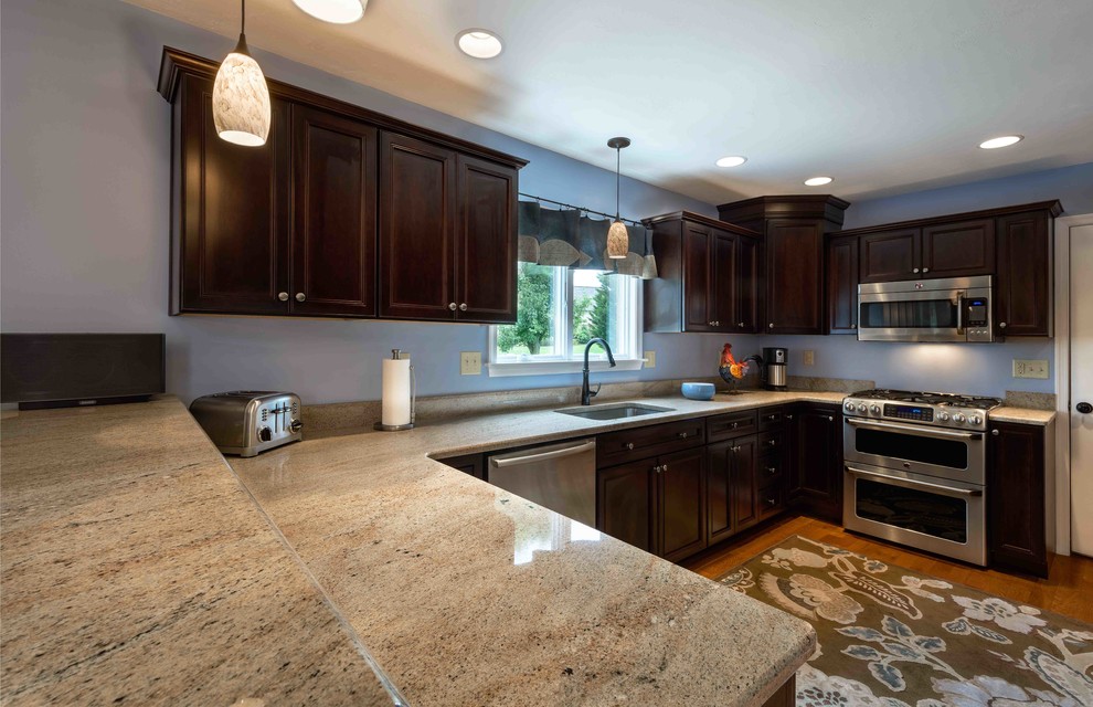 Inspiration for a mid-sized transitional u-shaped medium tone wood floor and brown floor enclosed kitchen remodel with an undermount sink, beaded inset cabinets, dark wood cabinets, granite countertops, stainless steel appliances and an island