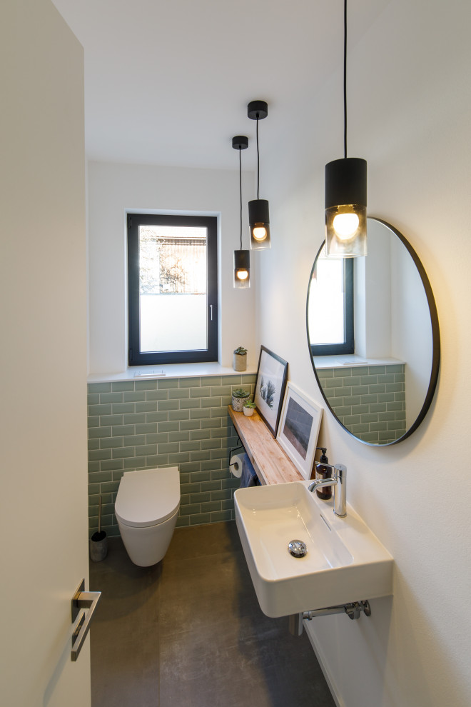 Photo of a mid-sized modern powder room in Munich with green tile, ceramic tile, ceramic floors, a wall-mount sink and grey floor.
