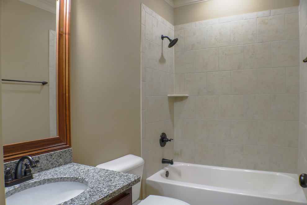 Photo of a mid-sized traditional 3/4 bathroom in Atlanta with an alcove tub, an alcove shower, a two-piece toilet, beige tile, ceramic tile, beige walls, an undermount sink, granite benchtops and a shower curtain.