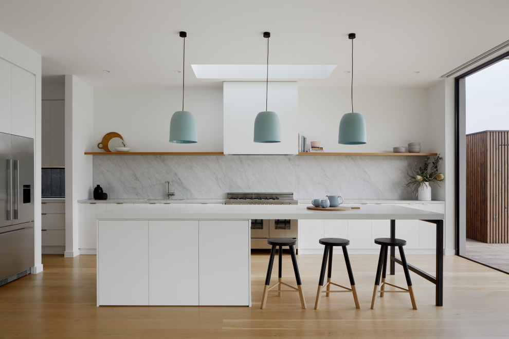 Design ideas for a contemporary open plan kitchen in Melbourne with marble worktops, marble splashback, stainless steel appliances, an island, flat-panel cabinets, white cabinets and light hardwood flooring.