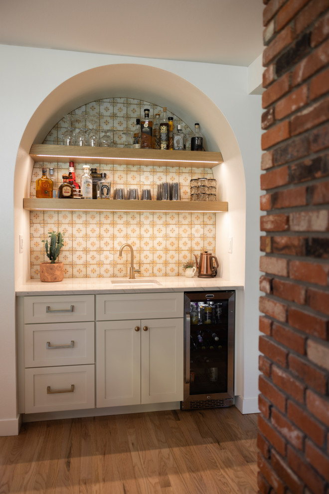 Inspiration for a large wet bar in Denver with an undermount sink, shaker cabinets, light wood cabinets, quartzite benchtops, multi-coloured benchtop, multi-coloured splashback, ceramic splashback and light hardwood floors.
