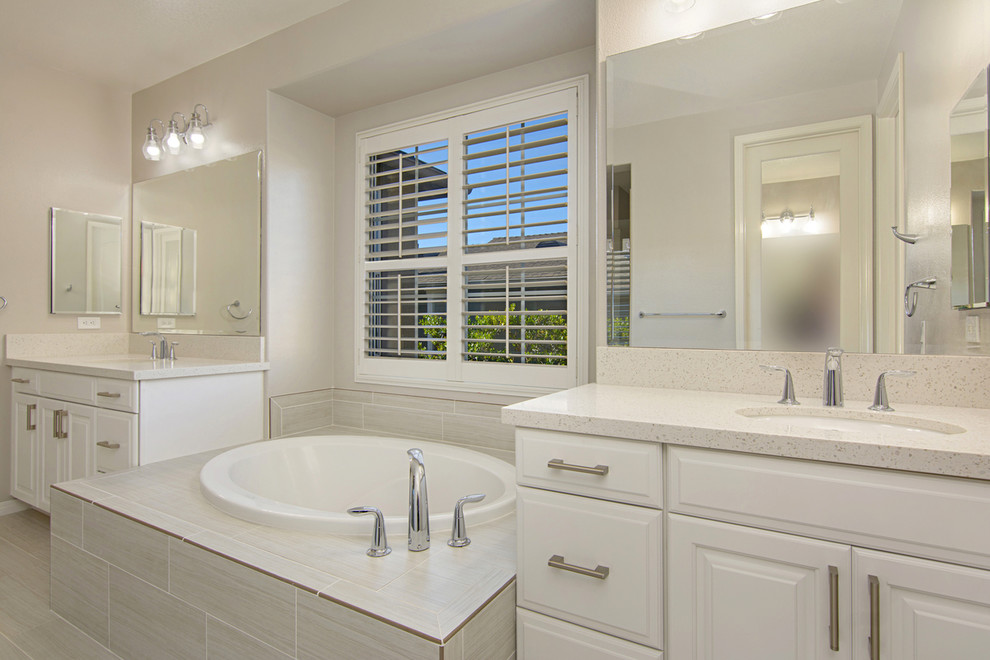 This is an example of a large modern master bathroom in San Diego with recessed-panel cabinets, white cabinets, a drop-in tub, an alcove shower, a two-piece toilet, yellow tile, ceramic tile, white walls, porcelain floors, engineered quartz benchtops, a hinged shower door, an undermount sink, white floor, white benchtops, a double vanity and a built-in vanity.