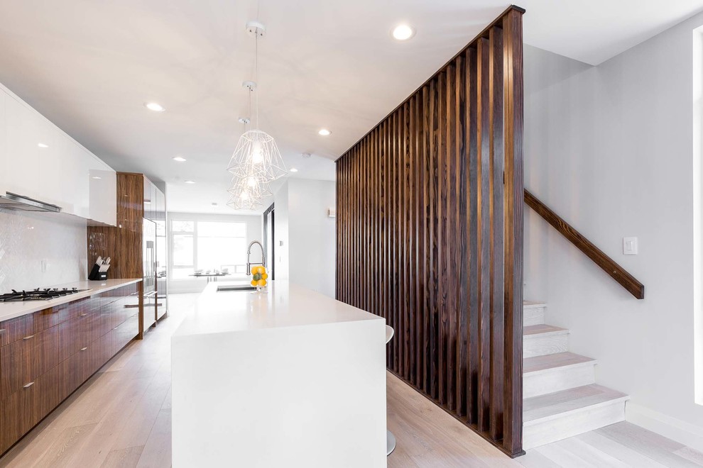 Example of a mid-sized trendy single-wall light wood floor eat-in kitchen design in Edmonton with an undermount sink, flat-panel cabinets, granite countertops, white backsplash, stainless steel appliances and an island