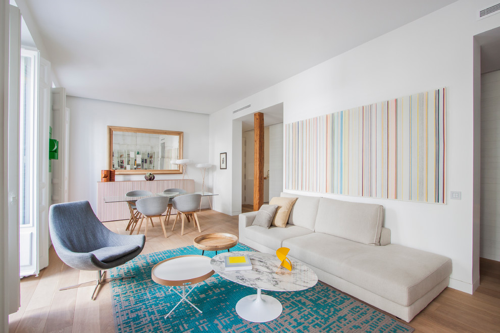 This is an example of a large scandinavian formal open concept living room in Madrid with white walls, light hardwood floors, no fireplace and no tv.