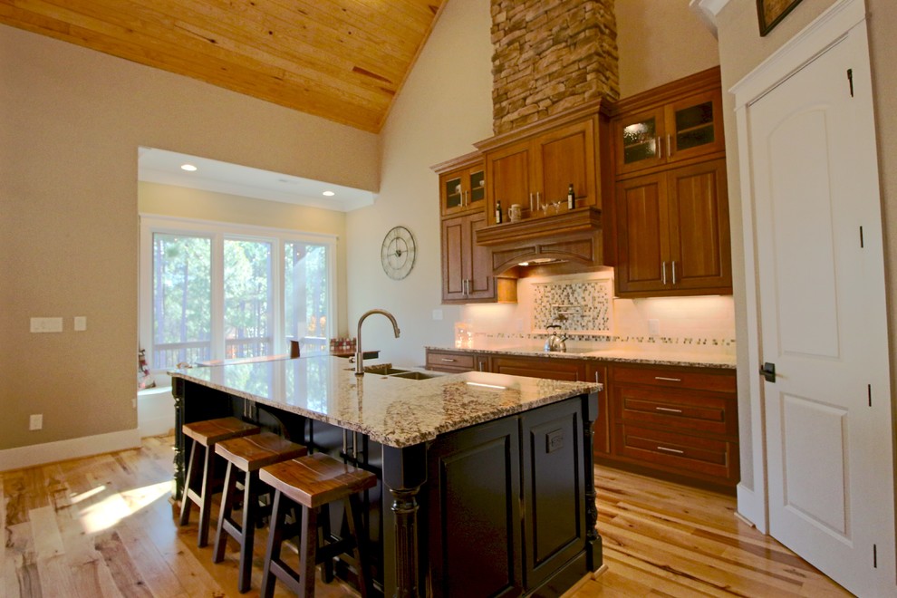 Mid-sized transitional l-shaped light wood floor and beige floor kitchen pantry photo in Raleigh with a farmhouse sink, raised-panel cabinets, medium tone wood cabinets, granite countertops, multicolored backsplash, glass tile backsplash, stainless steel appliances, an island and brown countertops