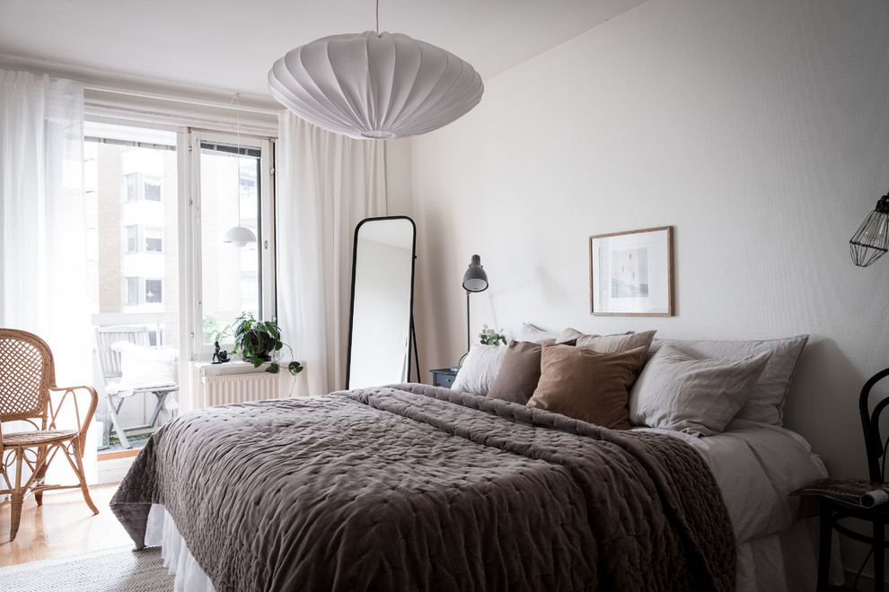 Design ideas for a scandinavian bedroom in Gothenburg with white walls, medium hardwood floors and brown floor.