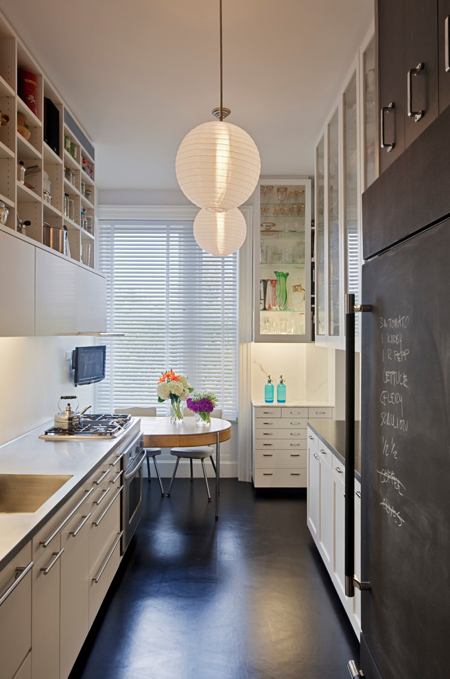 Mid-sized modern galley separate kitchen in New York with an integrated sink, flat-panel cabinets, white cabinets, stainless steel benchtops, white splashback, stainless steel appliances and linoleum floors.