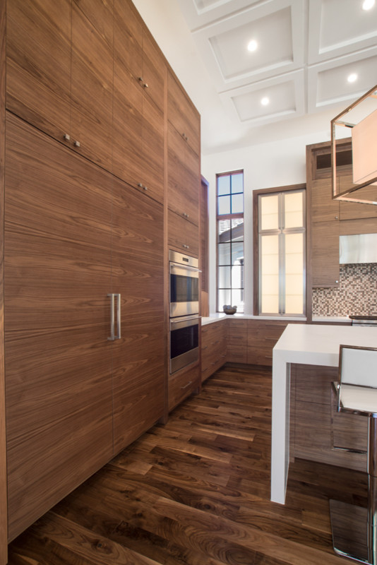 Photo of a large contemporary l-shaped eat-in kitchen in Miami with flat-panel cabinets, medium wood cabinets, quartz benchtops, brown splashback, mosaic tile splashback, panelled appliances and with island.