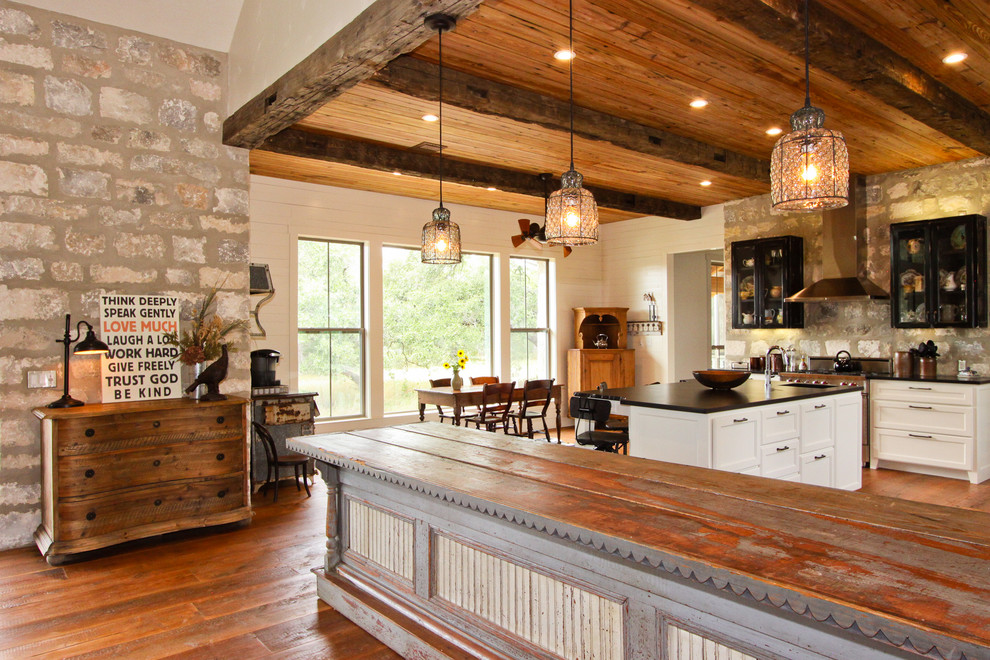 Inspiration for a large country u-shaped eat-in kitchen in Austin with an undermount sink, shaker cabinets, white cabinets, soapstone benchtops, grey splashback, stone tile splashback, stainless steel appliances, medium hardwood floors, with island and black benchtop.