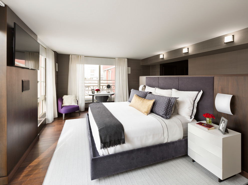 This is an example of a modern master bedroom in New York with brown walls and medium hardwood floors.