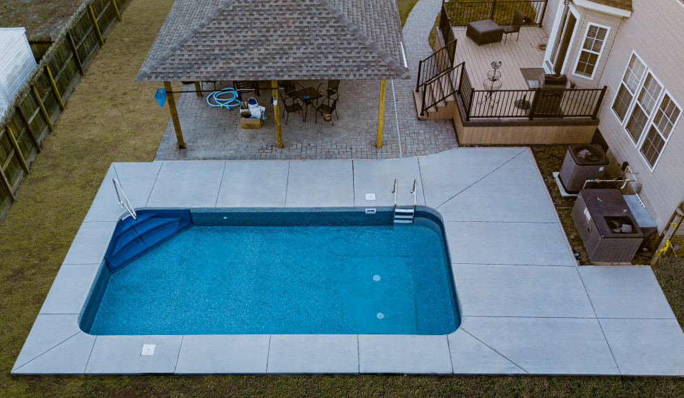 Inspiration for a large modern back rectangular lengths swimming pool in Other with with pool landscaping and concrete slabs.