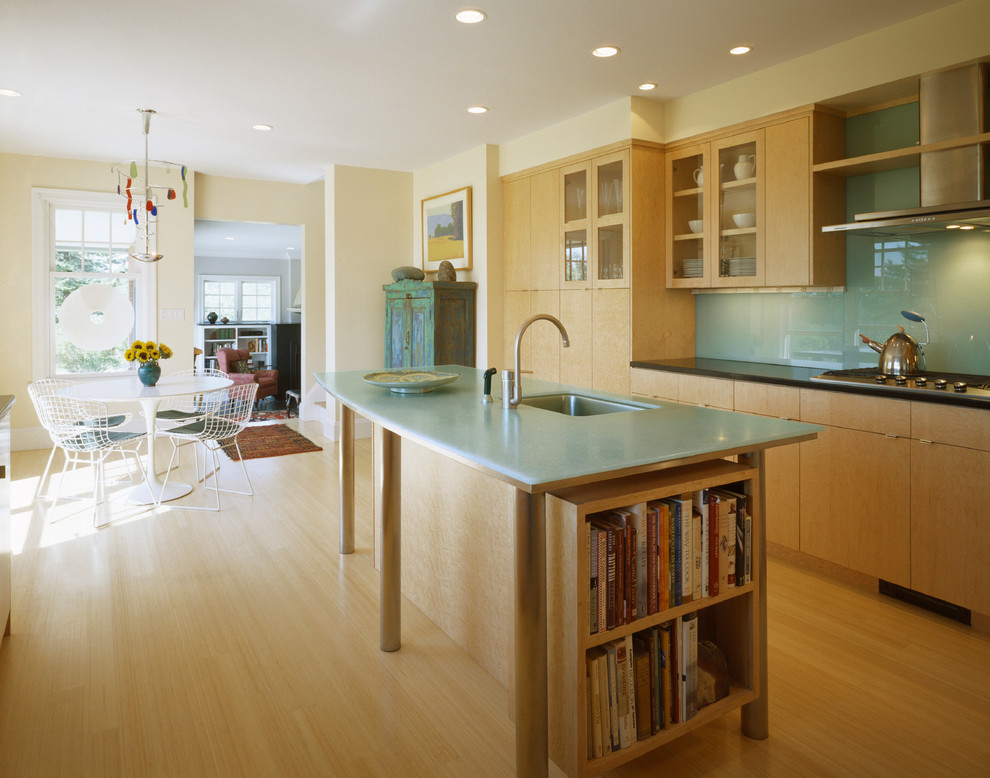 Photo of a mid-sized modern l-shaped eat-in kitchen in Portland Maine with an undermount sink, flat-panel cabinets, light wood cabinets, solid surface benchtops, blue splashback, glass sheet splashback, stainless steel appliances, bamboo floors and with island.