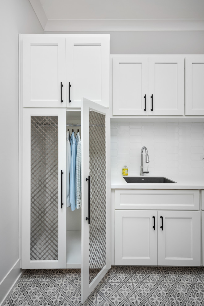 Country laundry room in Chicago with a single-bowl sink, shaker cabinets, white cabinets, white splashback, grey walls, multi-coloured floor and white benchtop.