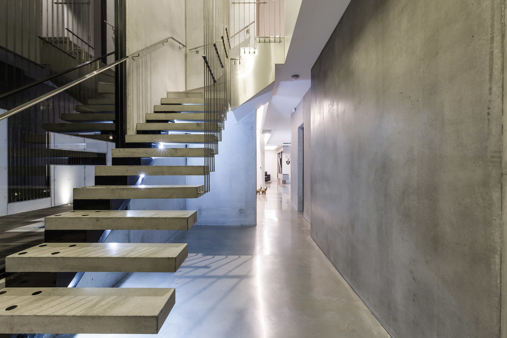 This is an example of a mid-sized modern concrete floating staircase in Brisbane with open risers and metal railing.