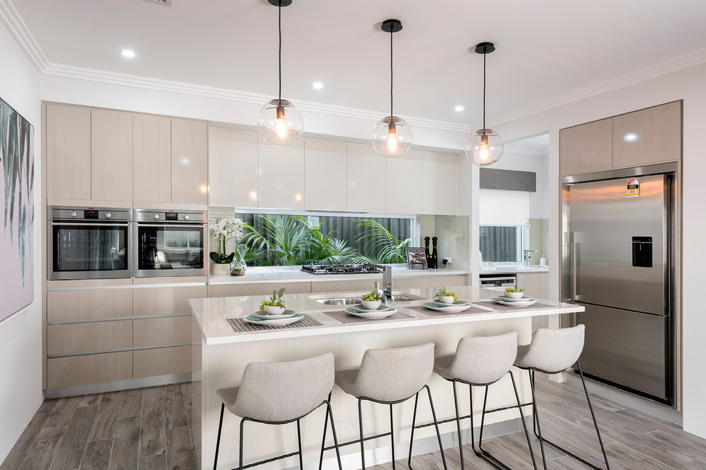 Inspiration for a mid-sized contemporary galley open plan kitchen in Perth with a double-bowl sink, flat-panel cabinets, light wood cabinets, quartz benchtops, glass sheet splashback, stainless steel appliances, porcelain floors and with island.
