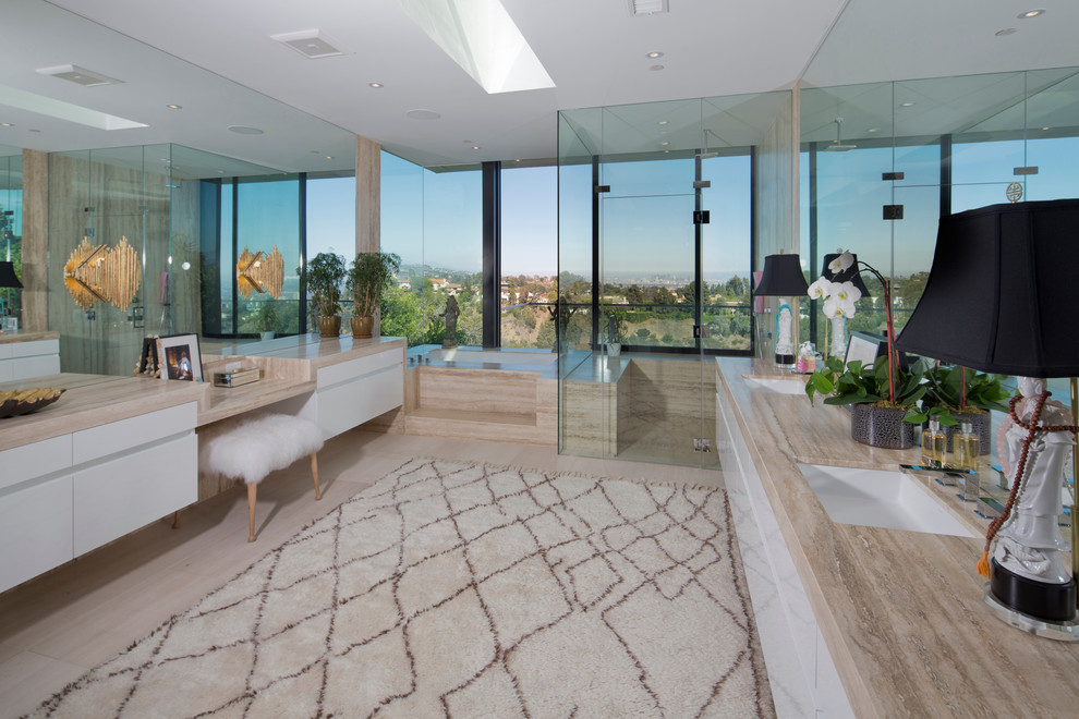 Inspiration for an expansive contemporary master bathroom in Los Angeles with flat-panel cabinets, white cabinets, an undermount tub, a corner shower, beige tile, limestone, porcelain floors, an undermount sink and limestone benchtops.