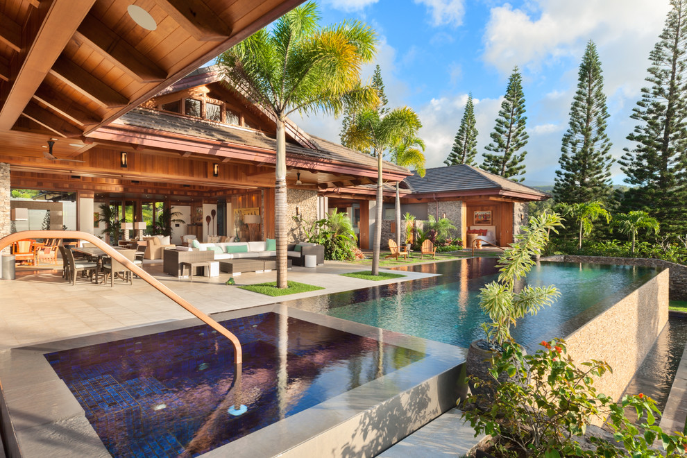 Photo of a large tropical backyard rectangular infinity pool in Hawaii with a hot tub and concrete slab.