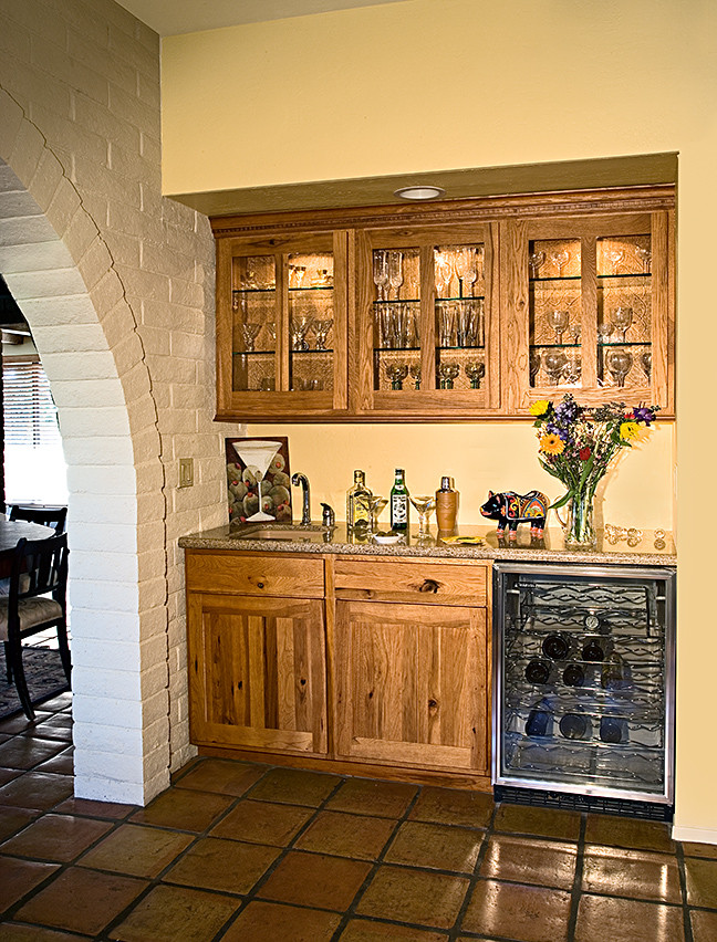 Small country single-wall wet bar in Phoenix with an undermount sink, shaker cabinets, medium wood cabinets, solid surface benchtops and terra-cotta floors.