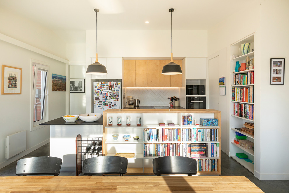 Design ideas for a small scandinavian galley open plan kitchen in Canberra - Queanbeyan with a double-bowl sink, flat-panel cabinets, white splashback, ceramic splashback, stainless steel appliances, concrete floors, with island, grey floor and black benchtop.