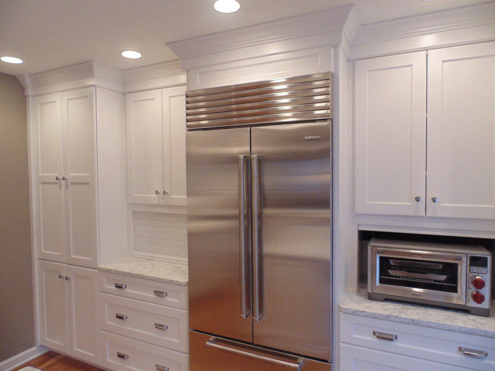 Large transitional u-shaped medium tone wood floor and brown floor eat-in kitchen photo with an undermount sink, recessed-panel cabinets, white cabinets, quartz countertops, white backsplash, subway tile backsplash, stainless steel appliances, an island and white countertops