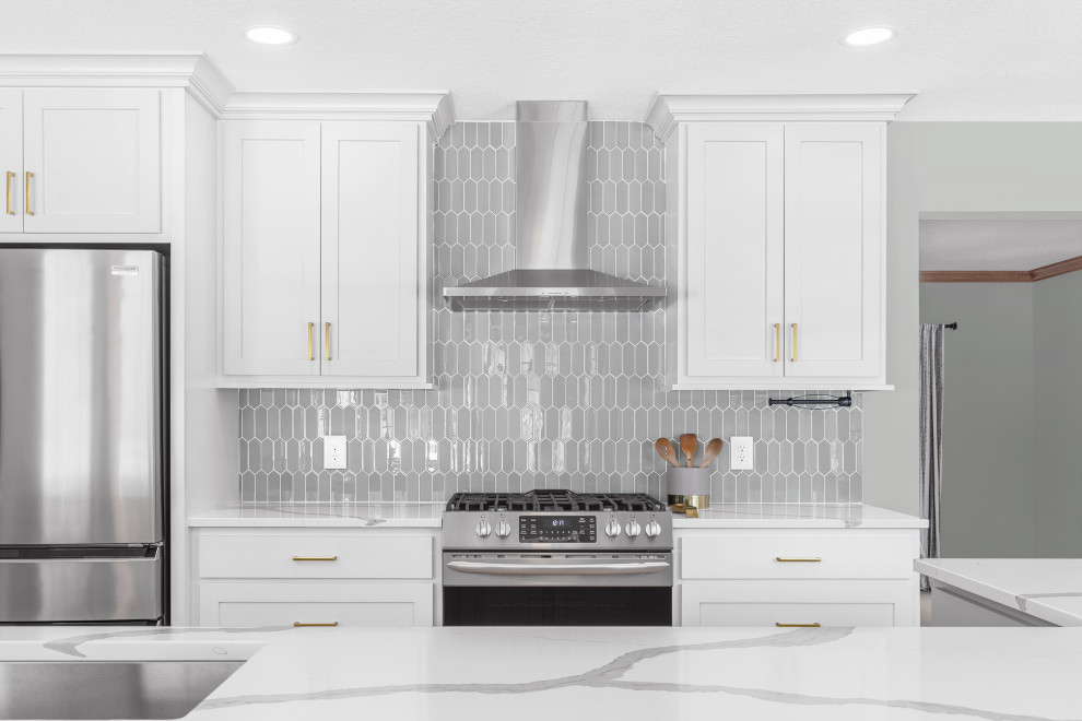 Mid-sized transitional l-shaped light wood floor and brown floor eat-in kitchen photo in Minneapolis with an undermount sink, recessed-panel cabinets, gray cabinets, quartz countertops, gray backsplash, glass tile backsplash, stainless steel appliances, an island and white countertops