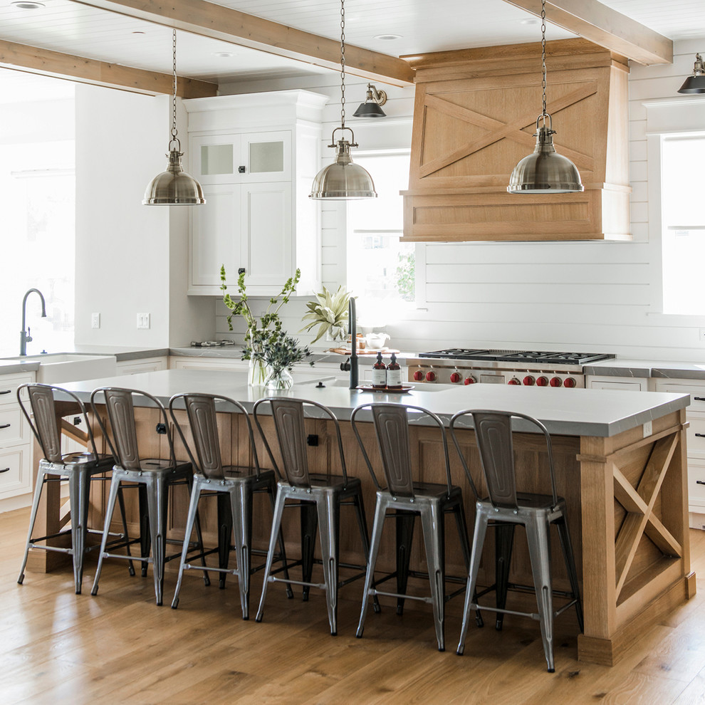 Inspiration for a large country eat-in kitchen in Salt Lake City with quartz benchtops, a farmhouse sink, shaker cabinets, white cabinets, white splashback, timber splashback, medium hardwood floors, with island and beige floor.
