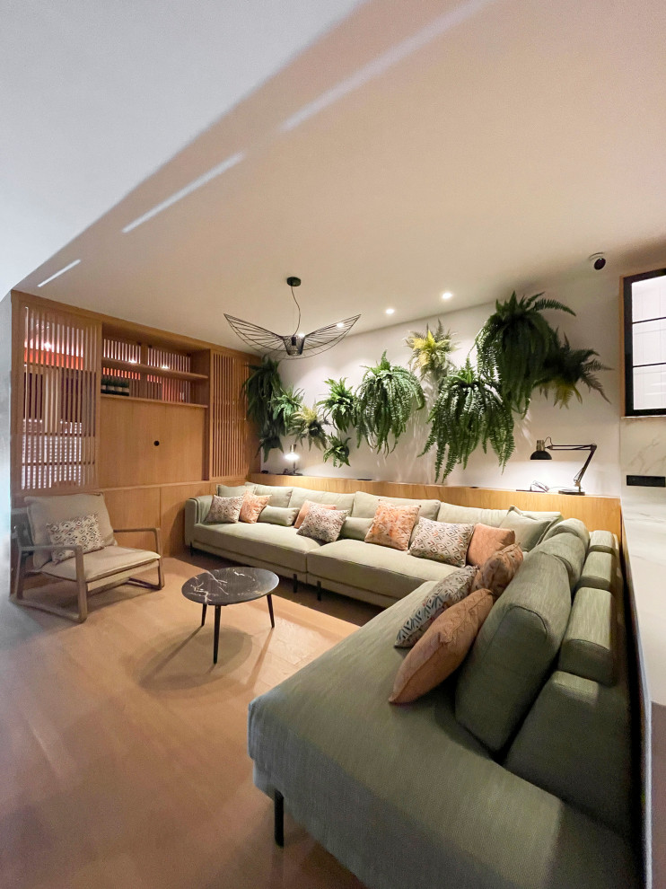 Diseño de biblioteca en casa abierta tropical de tamaño medio con paredes blancas, suelo de madera en tonos medios, pared multimedia y suelo marrón