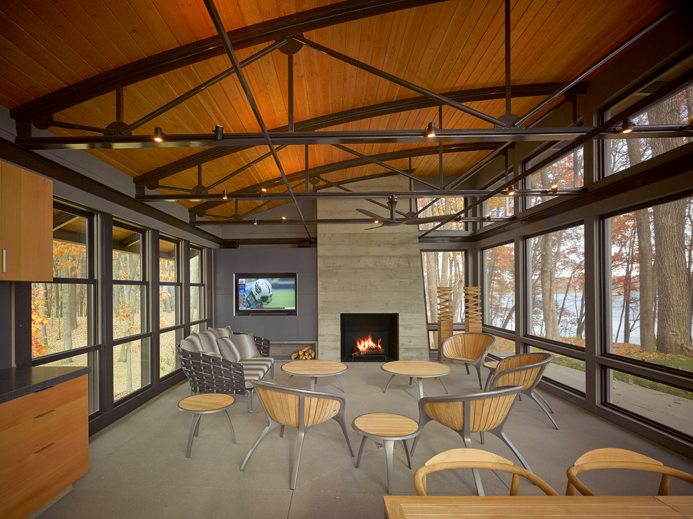 This is an example of an expansive modern side yard verandah in Minneapolis with a fire feature, concrete slab and a roof extension.
