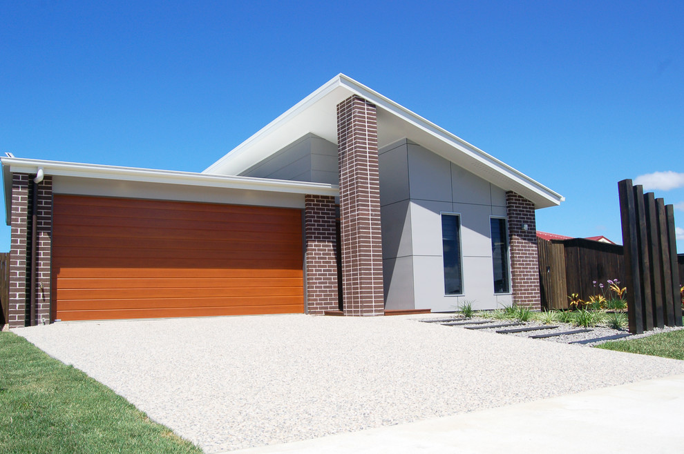 Small contemporary one-storey brick grey house exterior in Other with a shed roof and a metal roof.