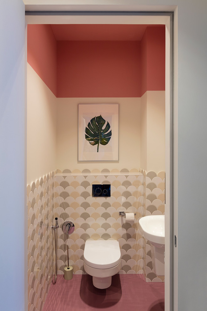Inspiration for a contemporary powder room in Moscow with a wall-mount toilet, pink floor and multi-coloured walls.