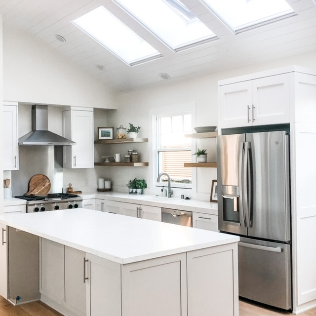 Inspiration for a medium sized classic l-shaped kitchen/diner in Orange County with a submerged sink, shaker cabinets, white cabinets, engineered stone countertops, metallic splashback, stainless steel appliances, light hardwood flooring, an island, white worktops and a wood ceiling.