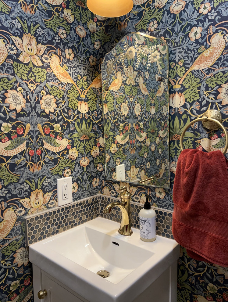 This is an example of a small traditional powder room in Boston with shaker cabinets, white cabinets, a one-piece toilet, multi-coloured walls, brick floors, a wall-mount sink, solid surface benchtops, red floor, white benchtops, a built-in vanity and wallpaper.