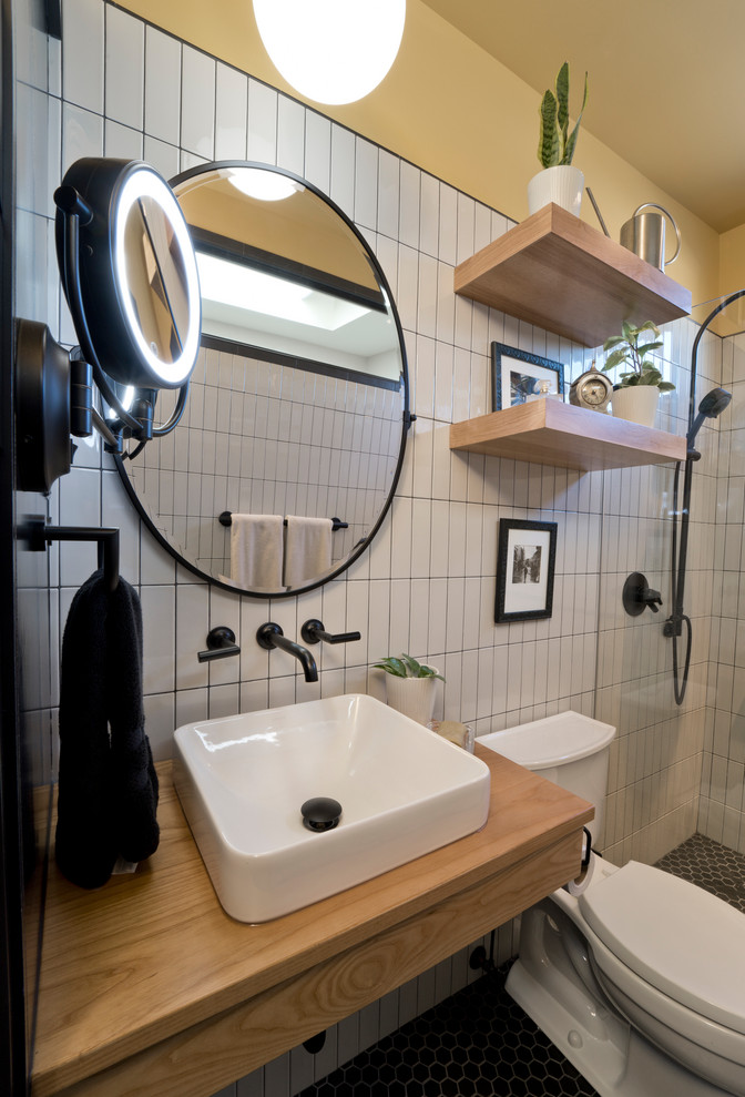Photo of a mid-sized contemporary master bathroom in DC Metro with shaker cabinets, medium wood cabinets, a curbless shower, a bidet, brown tile, porcelain tile, grey walls, mosaic tile floors, a vessel sink, granite benchtops, black floor, an open shower, black benchtops, a niche, a single vanity and a freestanding vanity.