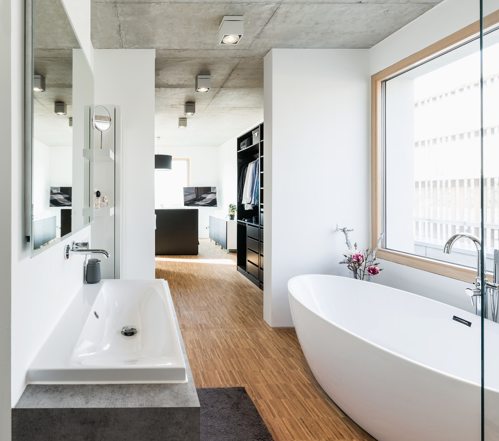Inspiration for an expansive modern master bathroom in Nuremberg with open cabinets, black cabinets, a freestanding tub, a curbless shower, a two-piece toilet, white walls, light hardwood floors, a vessel sink, solid surface benchtops, an open shower and white benchtops.